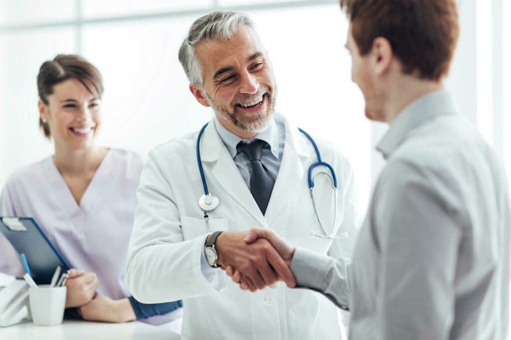Doctor with a broad smile shaking hands with a patient